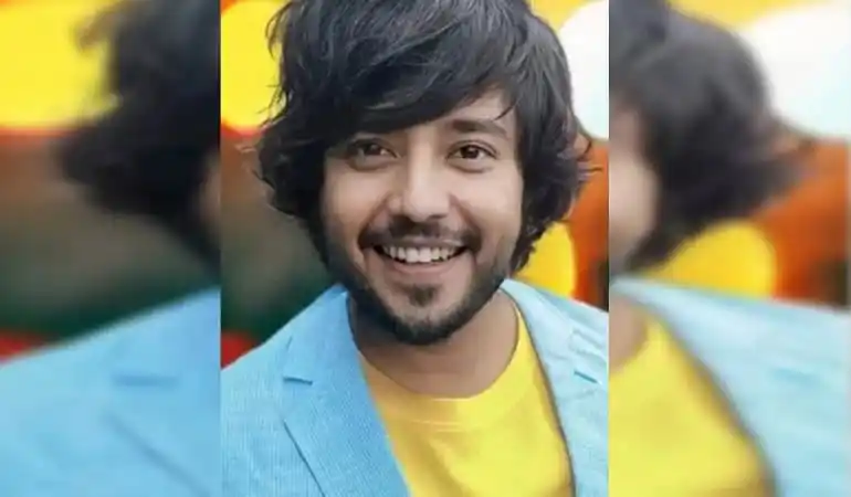 Smiling young man with black hair and beard in a blue blazer and yellow shirt. Channel i News - চ্যানেল আই নিউজ