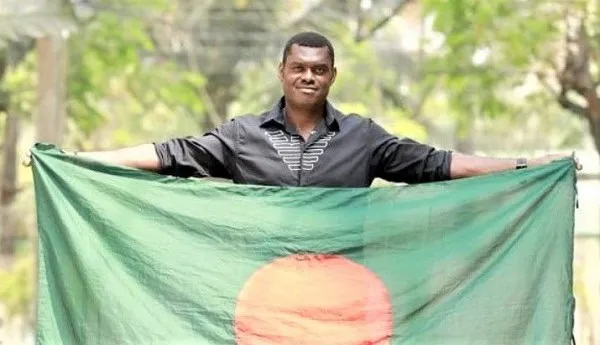 বাংলাদেশের পতাকা ধরে দাঁড়িয়ে থাকা যুবক, লাল-সবুজের জার্সি পরা. Channel i News - চ্যানেল আই নিউজ