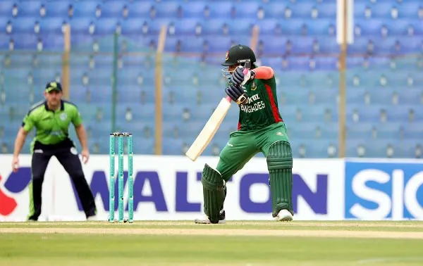 বাংলাদেশের ক্রিকেটার ব্যাটিং করছে, মাঠে খেলোয়াড় ও আম্পায়ার উপস্থিত. Channel i News - চ্যানেল আই নিউজ