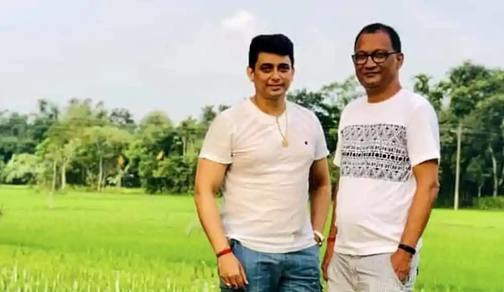 প্রাকৃতিক পরিবেশে দুইজন যুবক, সবুজ মাঠ ও গাছের পেছনে. Channel i News - চ্যানেল আই নিউজ