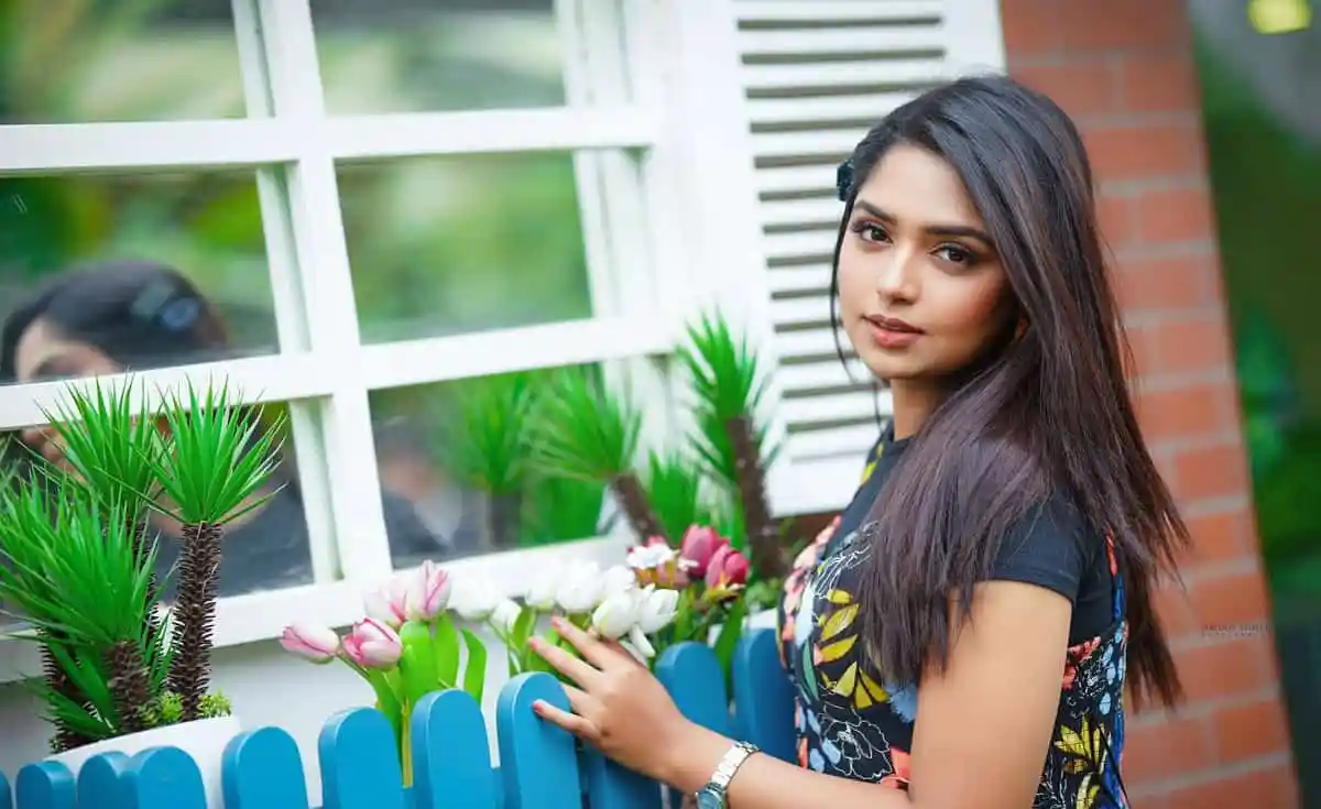 আনন্দিত তরুণী ফুলের পাশে দাঁড়িয়ে হাসছে. Channel i News - চ্যানেল আই নিউজ