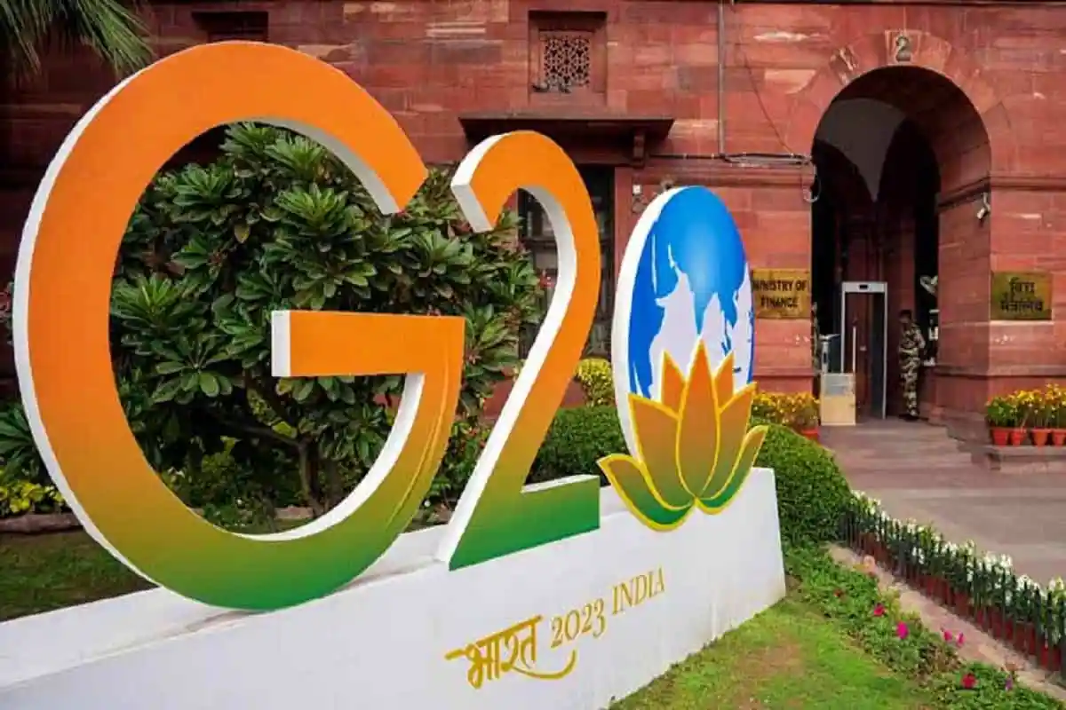 G20 India 2023 logo with lotus flower and greenery in front of red brick building. Channel i News - চ্যানেল আই নিউজ