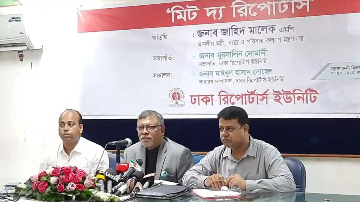 সংবাদ সম্মেলনে তিনজন বক্তা উপস্থিত, microphones ও ফুলের তোড়া সহ. Channel i News - চ্যানেল আই নিউজ