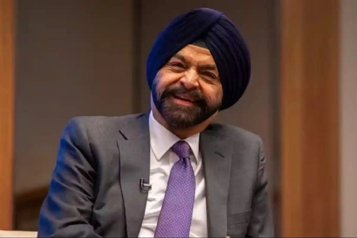 Smiling man wearing a blue turban and gray suit in an interview setting. Channel i News - চ্যানেল আই নিউজ