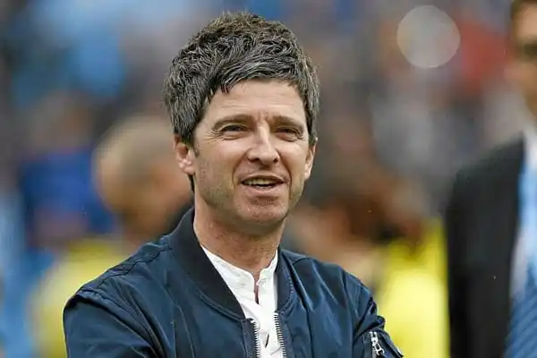 Man smiling outdoors in a sports setting, wearing a dark jacket. Channel i News - চ্যানেল আই নিউজ