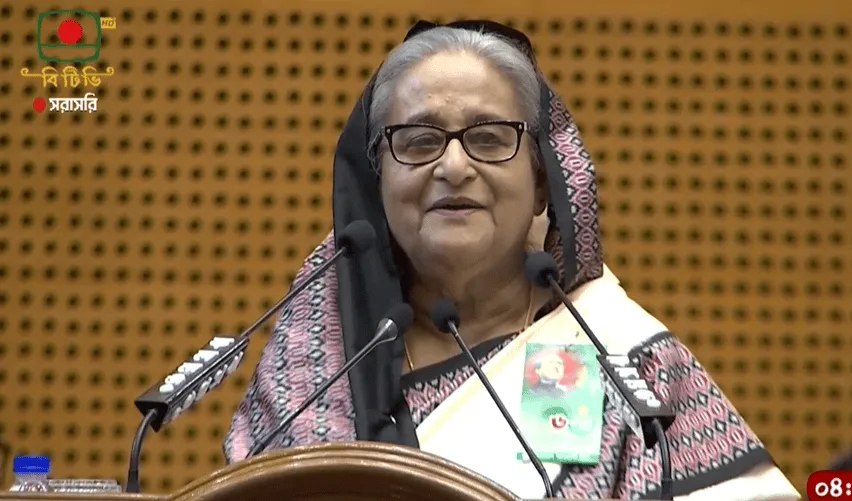 প্রধানমন্ত্রী শেখ হাসিনা ভাষণ দিচ্ছেন, পেছনে বাংলার পতাকা. Channel i News - চ্যানেল আই নিউজ