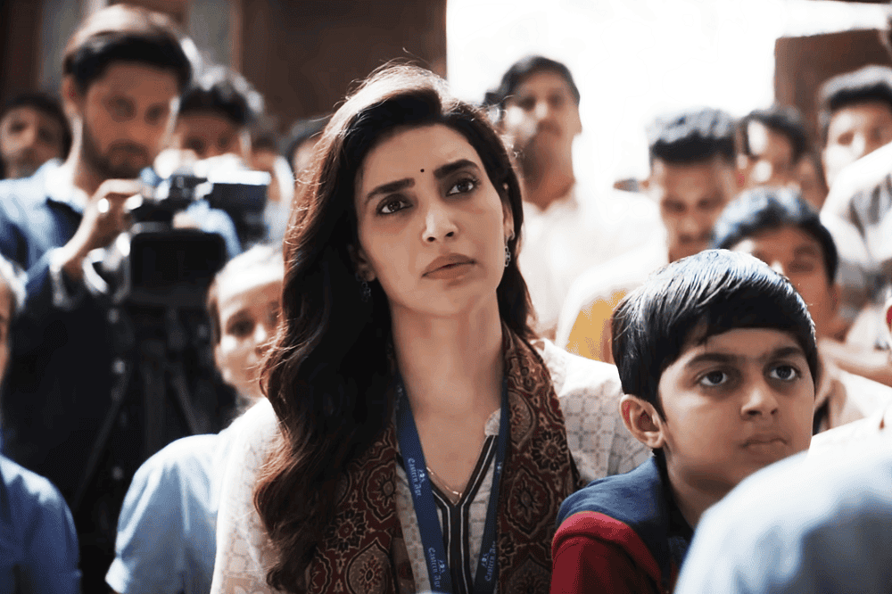 একজন নারী নেত্রী সমাবেশে বক্তৃতা দিচ্ছেন, পাশে শিশু ও দর্শকরা. Channel i News - চ্যানেল আই নিউজ