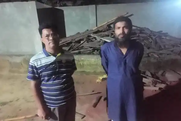 দুই ব্যক্তি ধ্বংসস্তূপের পাশে দাঁড়িয়ে, একটি নির্মাণাধীন বা ধ্বংসপ্রাপ্ত ভবনের সামনে. Channel i News - চ্যানেল আই নিউজ