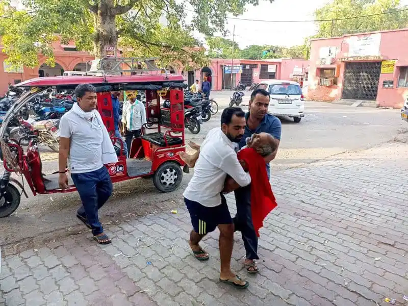 একজন ব্যক্তি অন্যজনকে সাহায্য করছেন, তীব্র গরমে অসুস্থ ব্যক্তির জন্য. Channel i News - চ্যানেল আই নিউজ