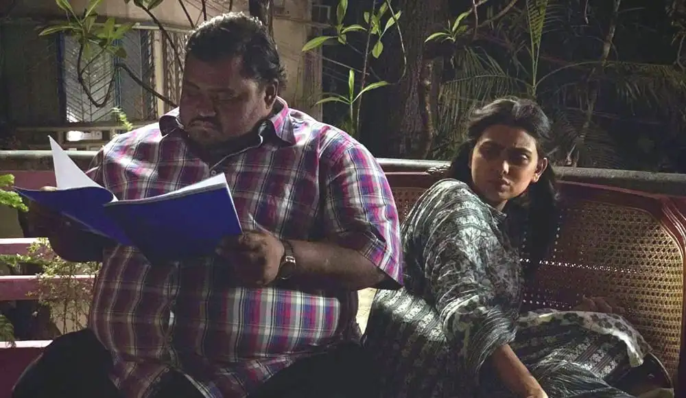 দুটি মানুষ বসে আছে, একজন বই পড়ছে, অন্যজন তাকিয়ে আছে. Channel i News - চ্যানেল আই নিউজ