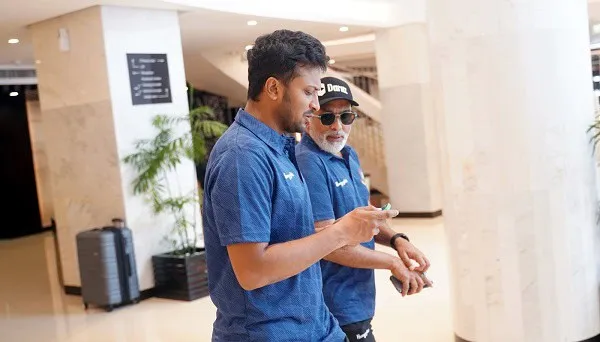 দুটি পুরুষ একসাথে মোবাইল ফোনে দেখছেন, বিমানবন্দরে অবস্থান।. Channel i News - চ্যানেল আই নিউজ