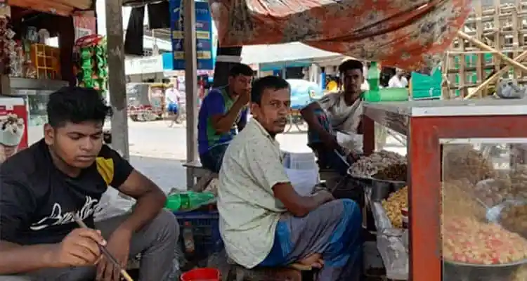 সিঙ্গারা বিক্রেতাদের একটি ছোট স্টলে বসে থাকা মানুষ. Channel i News - চ্যানেল আই নিউজ