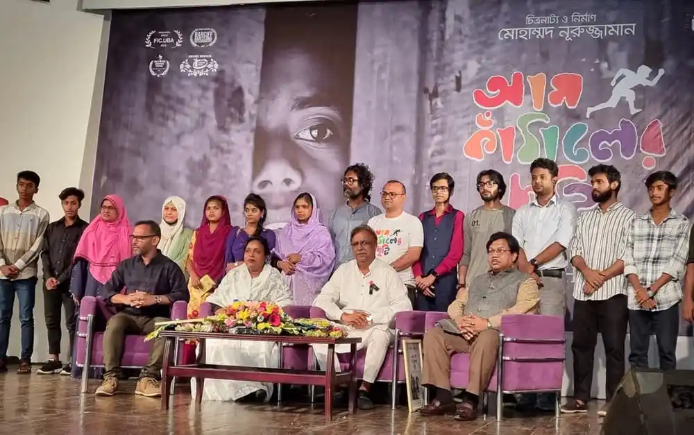 শিল্পী ও অতিথিরা এক অনুষ্ঠানে উপস্থিত, ব্যাকড্রপে সিনেমার পোস্টার দেখা যাচ্ছে. Channel i News - চ্যানেল আই নিউজ