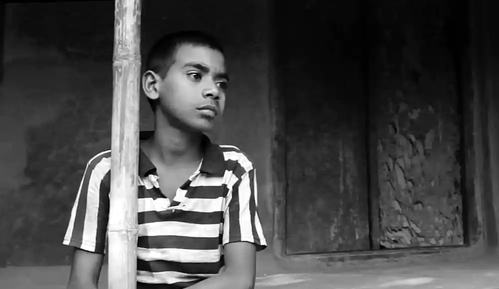 শিশু ছেলে একটি কাঠের খুঁটির পাশে দাঁড়িয়ে আছে. Channel i News - চ্যানেল আই নিউজ