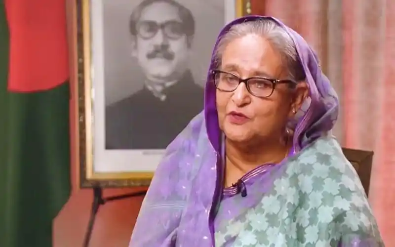 প্রধানমন্ত্রী শেখ হাসিনা বৈঠকে বক্তব্য দিচ্ছেন, পেছনে বঙ্গবন্ধুর ছবি. Channel i News - চ্যানেল আই নিউজ