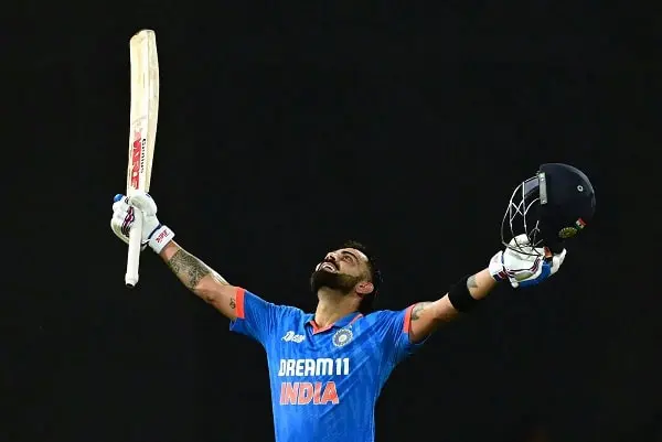 ক্রিকেটার কোহলি উল্লাসে ভাসছেন, হাতে ব্যাট ও হেলমেট উঁচু করে. Channel i News - চ্যানেল আই নিউজ