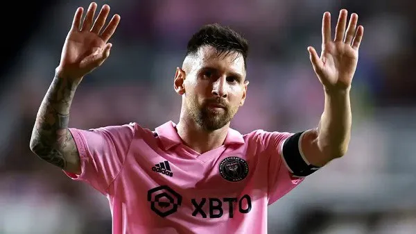 Lionel Messi in pink jersey waving to the crowd during a match. Channel i News - চ্যানেল আই নিউজ