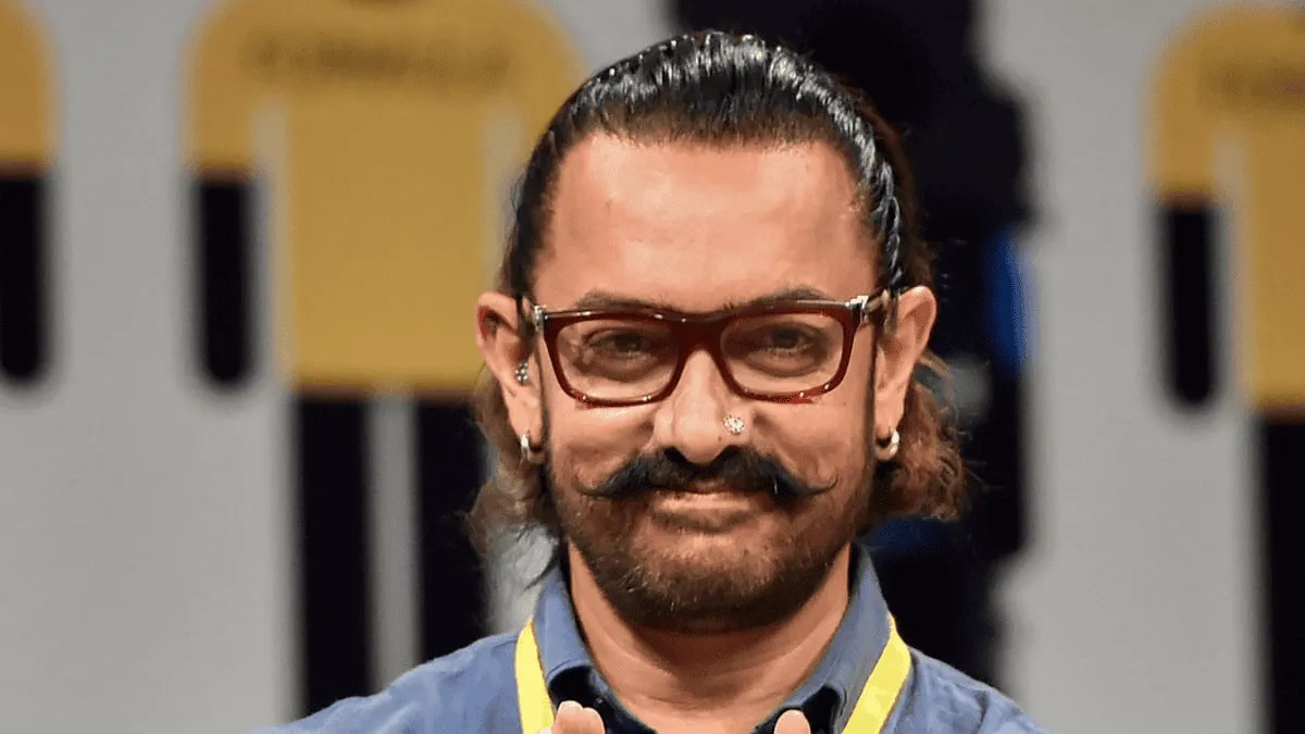 Amir Khan at an event, smiling with a mustache and glasses. Channel i News - চ্যানেল আই নিউজ