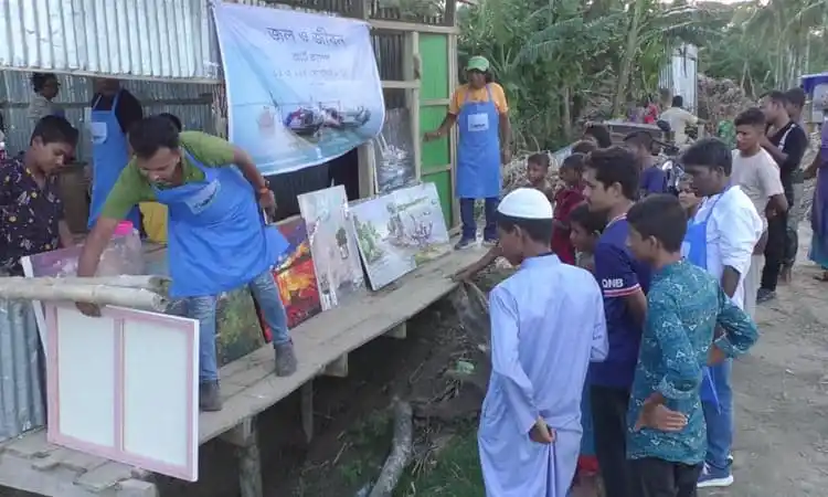 প্রদর্শনীতে দর্শকরা ছবি ও শিল্পকর্ম দেখছেন, মেঘনা নদীর পাড়ে অনুষ্ঠিত।. Channel i News - চ্যানেল আই নিউজ