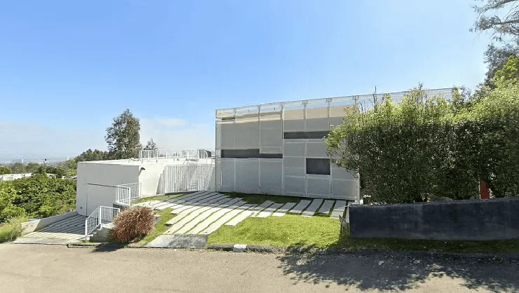 Modern white building with green lawn and trees under blue sky. Channel i News - চ্যানেল আই নিউজ