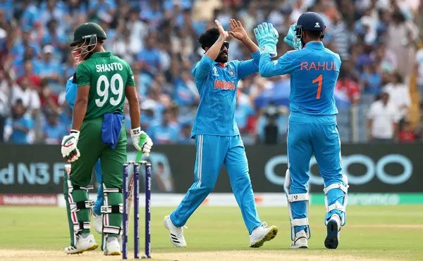 India cricket players celebrating during a match with Bangladesh players in the background. Channel i News - চ্যানেল আই নিউজ