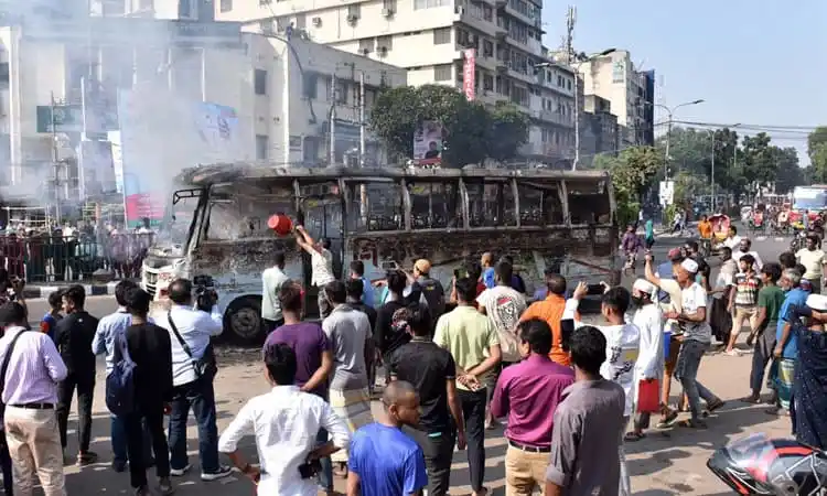 Burned bus in a crowded street during a protest in Bangladesh. Channel i News - চ্যানেল আই নিউজ