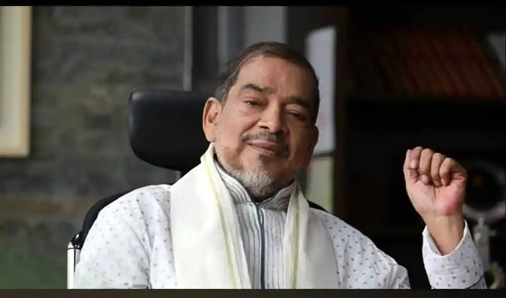 কাজী শাহেদ আহমেদ হাসিমুখে বসে, পেছনে বইয়ের তাক. Channel i News - চ্যানেল আই নিউজ