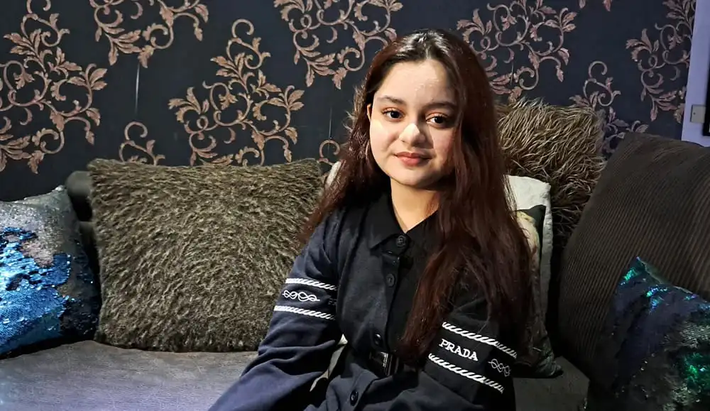 সোফায় বসে হাস্যোজ্জ্বল তরুণী, কালো পোশাক পরা. Channel i News - চ্যানেল আই নিউজ