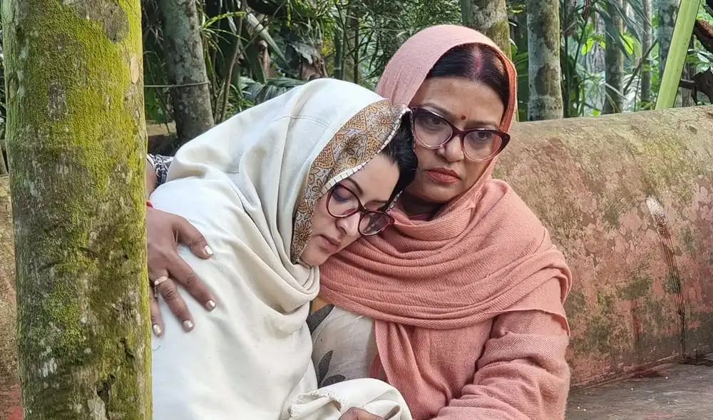 দুজন নারী বসে আছেন বনজঙ্গলে, একজন চোখে জল নিয়ে. Channel i News - চ্যানেল আই নিউজ