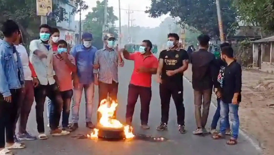 বিক্ষোভকারীরা রাস্তায় আগুন জ্বালিয়ে বিক্ষোভ করছেন, masks পরা।. Channel i News - চ্যানেল আই নিউজ