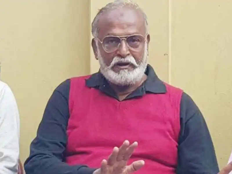 বৃদ্ধ ব্যক্তি গ্লাস পরা, সাদা চুল ও দাড়ি, কালো ও লাল পোশাক পরা. Channel i News - চ্যানেল আই নিউজ