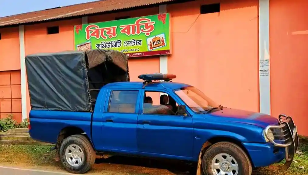 নীল রঙের পুলিশ ভ্যান গাড়ি, পেছনে একটি দোকানের সাইনবোর্ড দেখা যাচ্ছে. Channel i News - চ্যানেল আই নিউজ