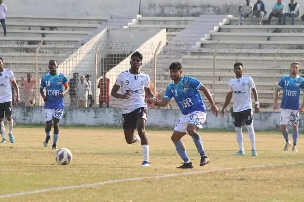 ফুটবল খেলোয়াড়রা মাঠে খেলছে, দর্শকরা স্টেডিয়ামে বসে দেখছেন. Channel i News - চ্যানেল আই নিউজ