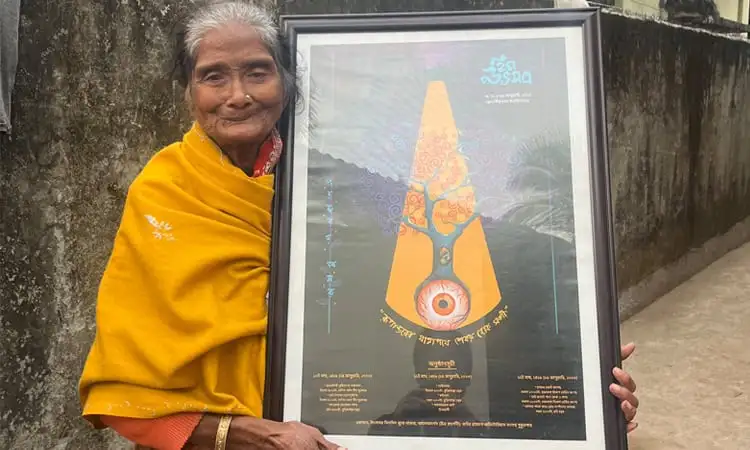 বৃদ্ধা নারী একটি framed চিত্রশিল্প ধরে আছেন, পটভূমিতে পাকা দেয়াল. Channel i News - চ্যানেল আই নিউজ