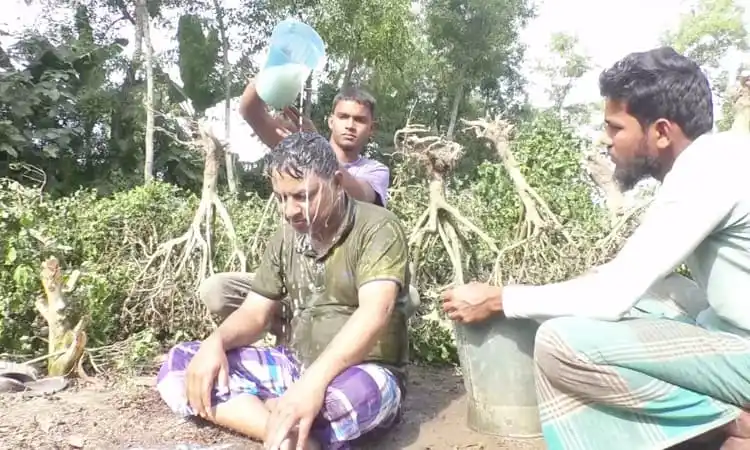 একজন ব্যক্তি দুধ দিয়ে গোসল করছেন, অন্যরা দেখছেন, প্রকৃতি পরিবেশে।. Channel i News - চ্যানেল আই নিউজ