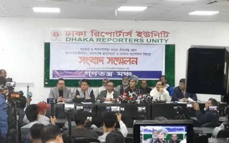 সংবাদ সম্মেলনে বিভিন্ন ব্যক্তি উপস্থিত, মিডিয়া ক্যামেরা ও সাংবাদিকরা উপস্থিত. Channel i News - চ্যানেল আই নিউজ
