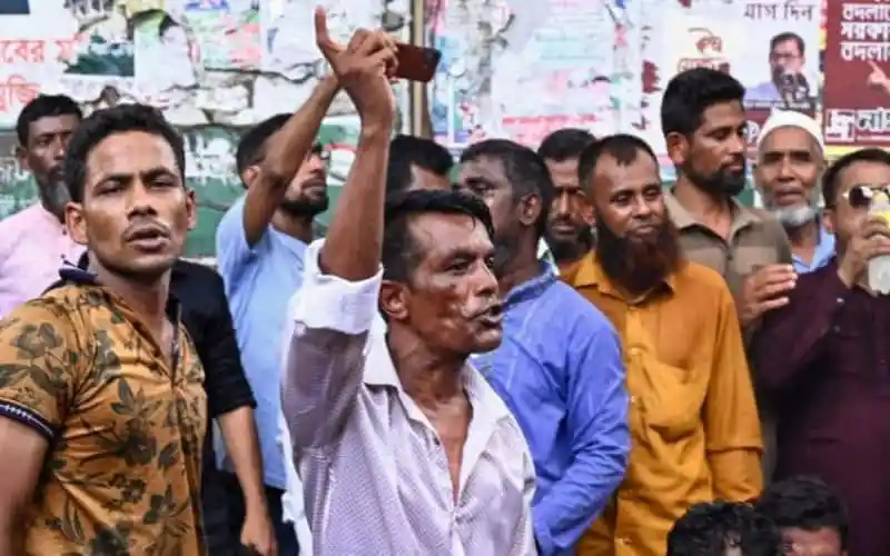 জনতা রাস্তায় দাঁড়িয়ে প্রতিবাদ জানাচ্ছে, ছবি তোলা হচ্ছে. Channel i News - চ্যানেল আই নিউজ