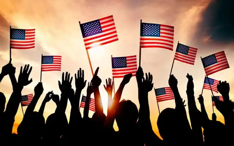 People holding American flags during sunset demonstration. Channel i News - চ্যানেল আই নিউজ