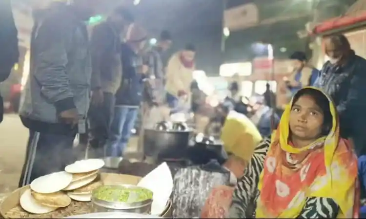 বাজারে ভিড়ের মধ্যে একজন মহিলা শীতের পিঠা বিক্রি করছেন।. Channel i News - চ্যানেল আই নিউজ