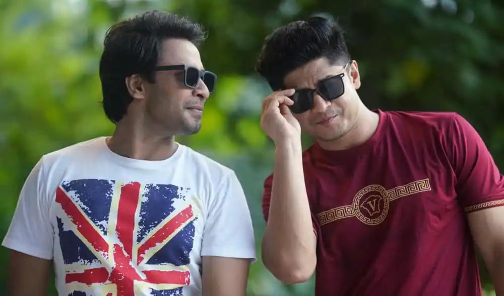 দুই যুবক সানগ্লাস পরে outdoors, একজন অন্যজনের দিকে তাকাচ্ছে. Channel i News - চ্যানেল আই নিউজ
