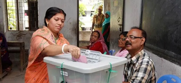 নির্বাচনে ভোট দিচ্ছেন একজন নারী ভোটার, অন্যরা দেখছেন. Channel i News - চ্যানেল আই নিউজ