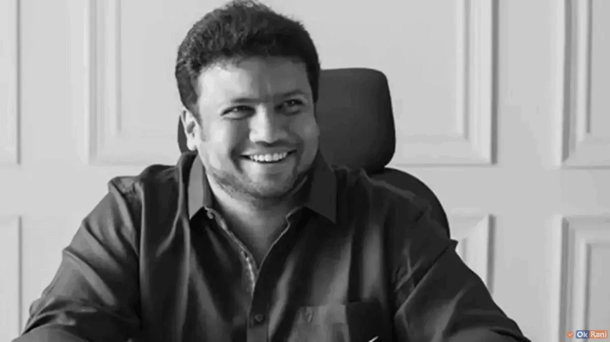 Smiling man in formal shirt sitting at desk in black and white photo. Channel i News - চ্যানেল আই নিউজ