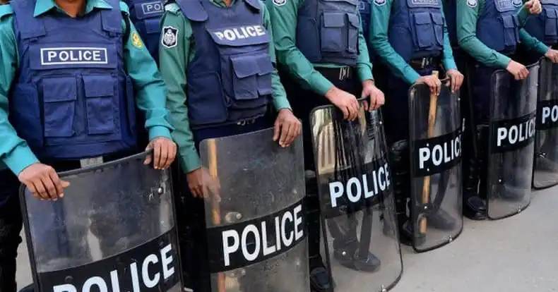 বাংলাদেশ পুলিশ সদস্যরা শারীরিক নিরাপত্তা সরঞ্জাম সহ দাঁড়িয়ে. Channel i News - চ্যানেল আই নিউজ