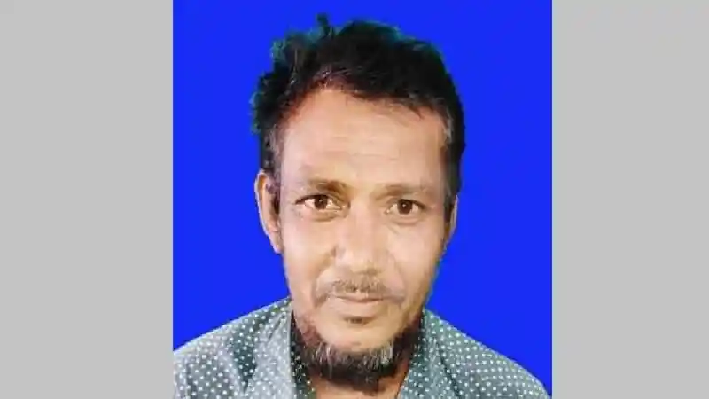 অভিযুক্ত ব্যক্তির ছবি, কালো চুল ও দাড়ি সহ, নীল পটভূমিতে. Channel i News - চ্যানেল আই নিউজ