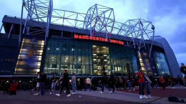 Manchester United stadium exterior with fans outside during evening. Channel i News - চ্যানেল আই নিউজ