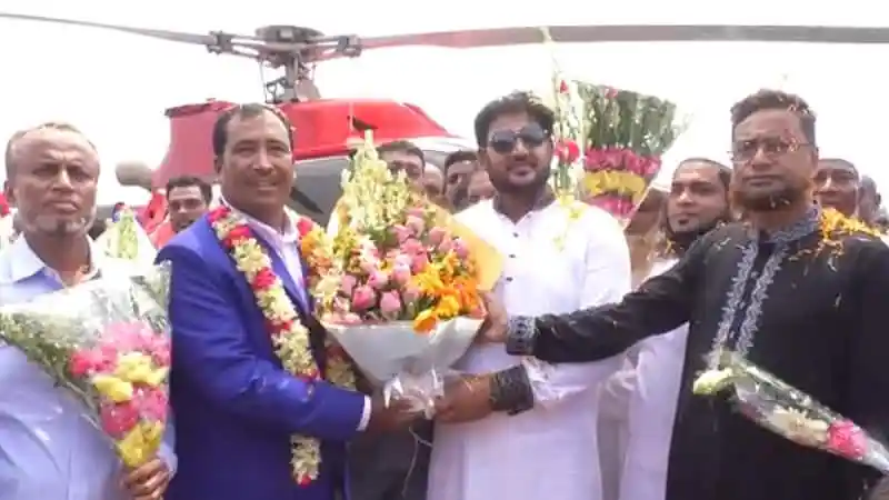 প্রবাসী ব্যক্তির বাড়ি ফেরার সময় ফুলের তোড়া গ্রহণ করছেন. Channel i News - চ্যানেল আই নিউজ