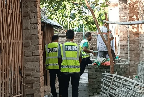 Police officers inspecting a narrow alleyway in a rural area of Bangladesh. Channel i News - চ্যানেল আই নিউজ