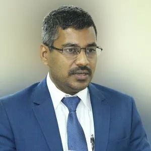 বাংলাদেশের একজন সরকারি কর্মকর্তা, পেশাদার পোশাক পরা, অফিসে কাজ করছেন. Channel i News - চ্যানেল আই নিউজ