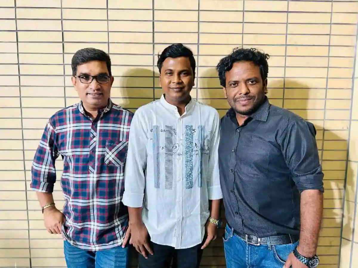তিনজন ব্যক্তি হাসিমুখে দাঁড়িয়ে আছেন, পটভূমিতে টাইলসের দেয়াল. Channel i News - চ্যানেল আই নিউজ