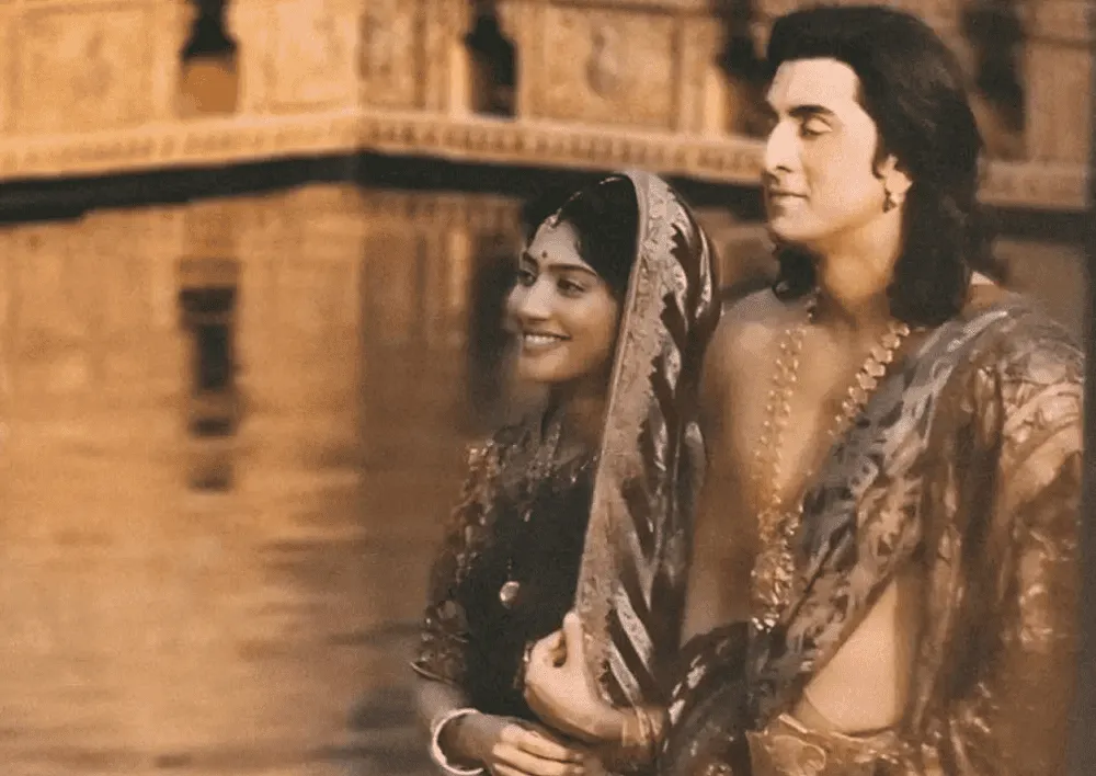 বৈচিত্র্যময় ঐতিহ্যবাহী পোশাক পরিহিত দুই ব্যক্তি নদীর পাশে দাঁড়িয়ে. Channel i News - চ্যানেল আই নিউজ